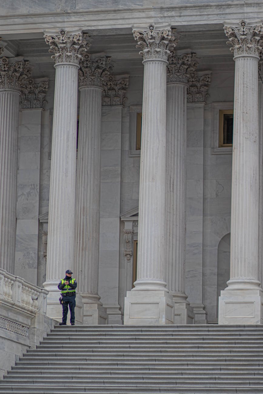 a police officer standing near white concrete pillars of a building